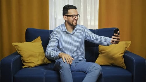 Cheerful Man On Video Call on Sofa Indoors