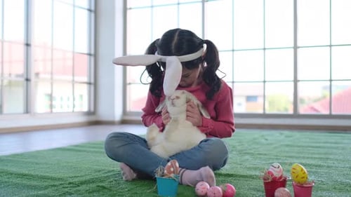 Girl Holds Rabbit Surrounded by Decorated Easter Eggs