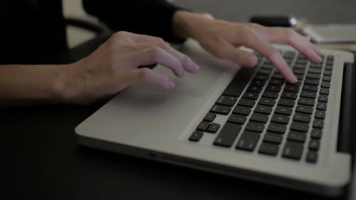 Hands typing on laptop keyboard at work