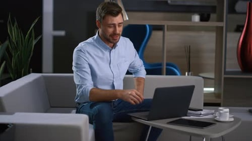 Excited Entrepreneur Leading Videoconference Using Laptop in Tech Company Office