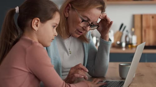 Grandmother and Girl Using Laptop Together at Home