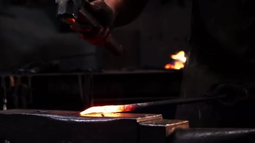Blacksmith Shaping Hot Metal with Hammer on Anvil