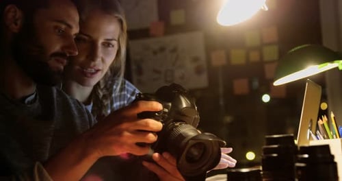 Man and Woman Reviewing Photos on Camera Screen