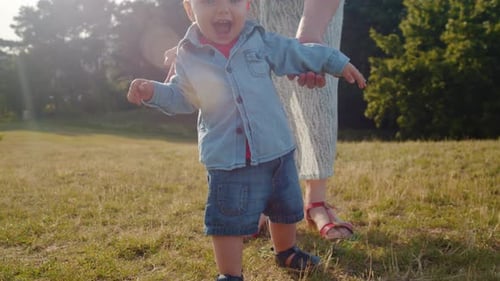 Child Takes the First Steps Walking in the Park with Mom