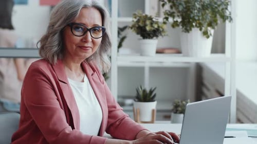 Beautiful Senior Businesswoman Posing for Camera at Office Desk