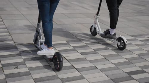 Un homme et une femme conduisent des scooters électriques
