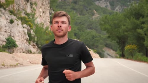 Porträt eines gutaussehenden, muskulösen Mannes, der auf der Straße in Bergen läuft.