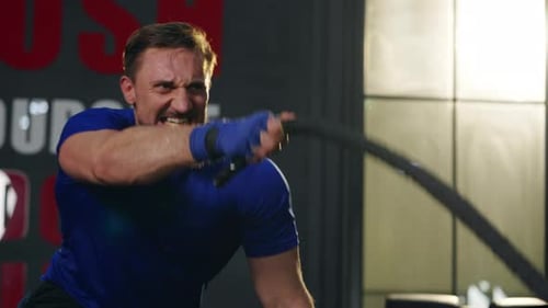 4K Caucasian man workout exercise with battle rope at gym