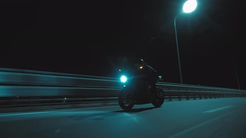 A Man Rides a Sports Motorcycle Through the City at Night