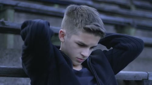 Einsamer männlicher Teenager auf Bank sitzend, Jugendprobleme, innerer Selbstprotest