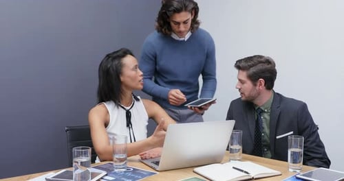 Team Discussing Business Around Table with Laptop