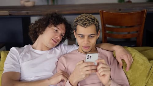 Gay Couple Relaxing on the Couch and Hugging Whatching the Smartphone Screen