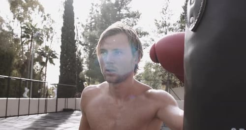 Man Boxing Heavy Bag Outside on Sunny Day