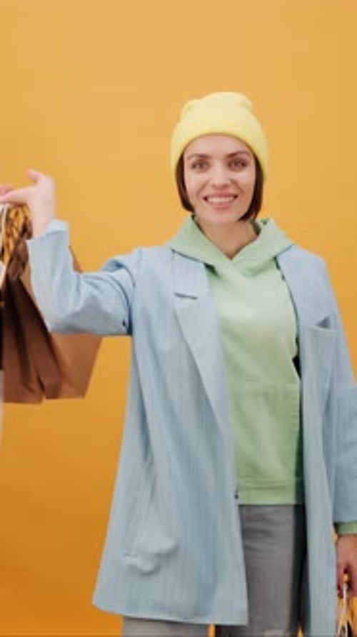 Smiling Woman with Shopping Bags on Yellow Background