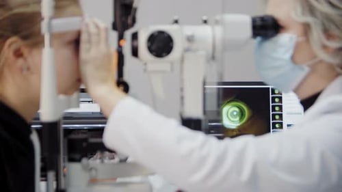 Der Augenarzt untersucht das Auge des Patienten und schaut dann in die Kamera