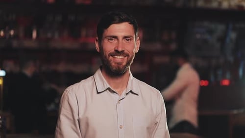 Portrait of Smiling Attractive Man Looking at Camera in a Bar or Beer Pub