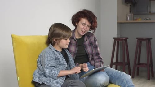 Child and Adult Interact with Tablet at Home