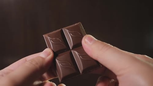 Un hombre rompe una barra de chocolate
