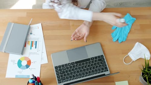High Angle View of Woman Employee Using Hand Sanitizer in Workplace Then Typing with Laptop