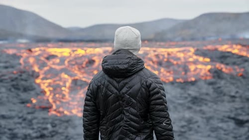 Person Contemplates Active Lava Flow Landscape