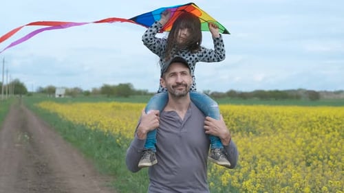 Happy Adult Carries Child with Kite in Rural Setting