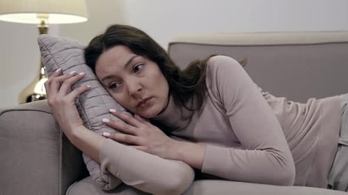 Woman Lying on Couch Hugging Pillow