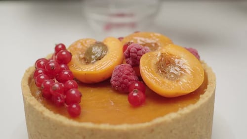 Hand Decorates Cake with Raspberries and Berries