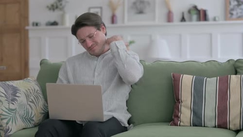 Man Massages Stiff Neck While Using Laptop