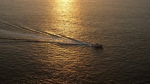 Motorboat Sails Along Calm Ocean with Sunlight Reflection