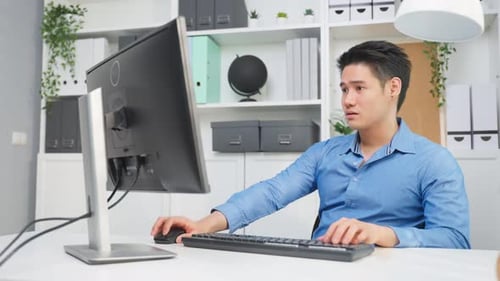 Asiatischer attraktiver Geschäftsmann, der auf dem Tisch sitzt und im Büro arbeitet.