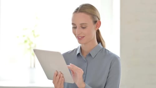 Young Woman Smiles Using a Tablet Device Indoors
