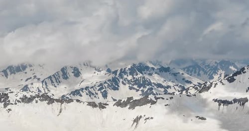 Air Flight Through Mountain Clouds Over Beautiful Snowcapped Peaks of Mountains and Glaciers