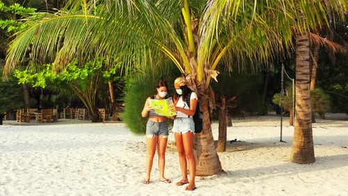 Pretty smiling ladies on vacation spending quality time at the beach on paradise white sand and blue