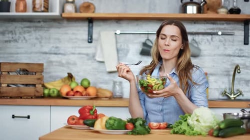 Woman Enjoys a Fresh Salad in Bright Kitchen