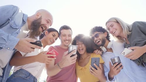 Diverse Friends Sharing a Laugh While Using Smartphones