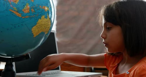 Little girl looking at globe in classroom