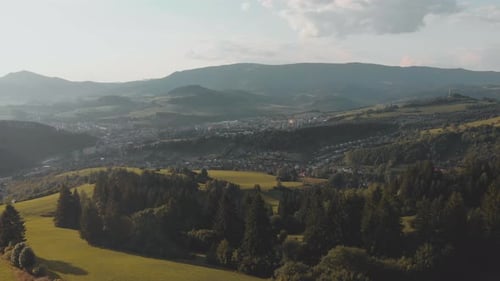 AERIAL View on cute little Mountain City on a sunny day and beautiful surrounding Landscape of fores