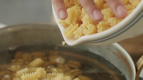 Pouring Uncooked Pasta into a Pot of Boiling Water