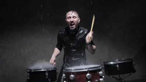 Man Plays Drums Vigorously in Heavy Rain