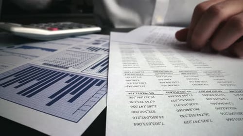 Accountant Analyzing Business Marketing Data on Paper Dashboard at Office Table