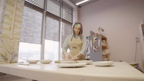 Woman Arranges Ceramic Bowls in Pottery Studio