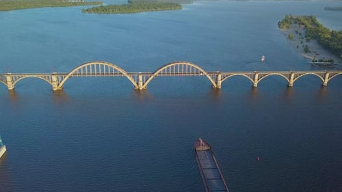 Ship Floating on River Under Bridge