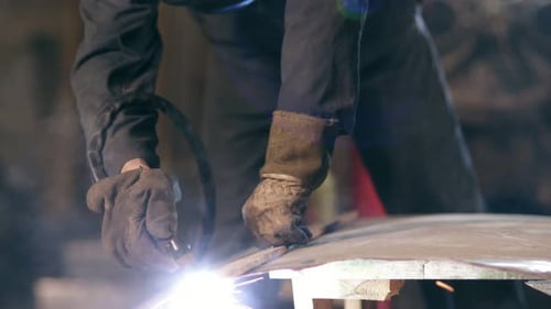 Hands of a Workman in Protective Gloves Holding Wood Plank to Adjust a Cutting Line on Metal