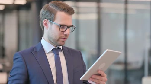 Man in Suit Celebrates with Tablet at Office