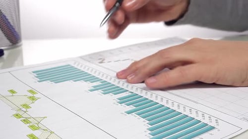 Analyzing Financial Charts with Pen in Workplace