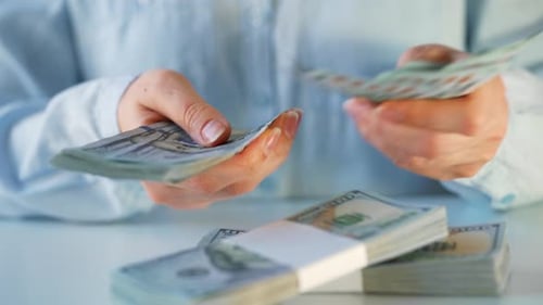 Hands Counting Money at a White Table