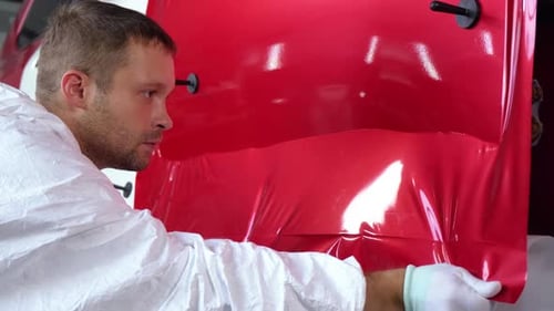 Car Detailer Applying Red Vinyl Wrap