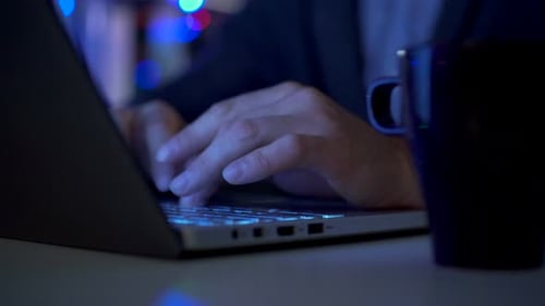 Hände eines Mannes, der spät in der Nacht am Computer arbeitet