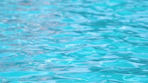 Nahaufnahme der Oberfläche von blauem klarem Wasser mit kleinen Wellenwellen im Schwimmbad