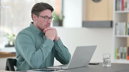 Man with Laptop Thinking in Home Office